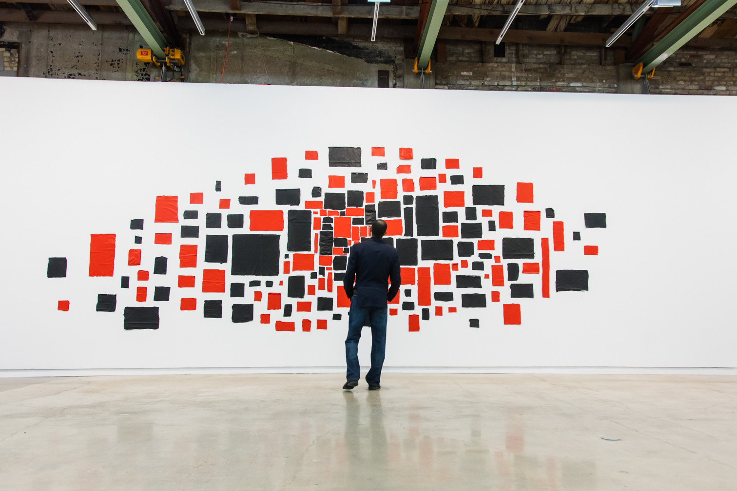 man stands in front of large wall-sized abstract art of colored rectangles of varying sizes