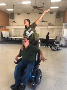 two dancers exploring ways to dance together. One dancer is a power wheelchair user.