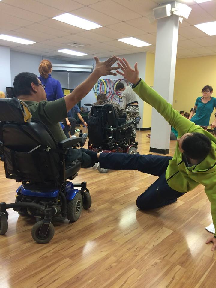 dancer in wheelchair joins hands with other dancer