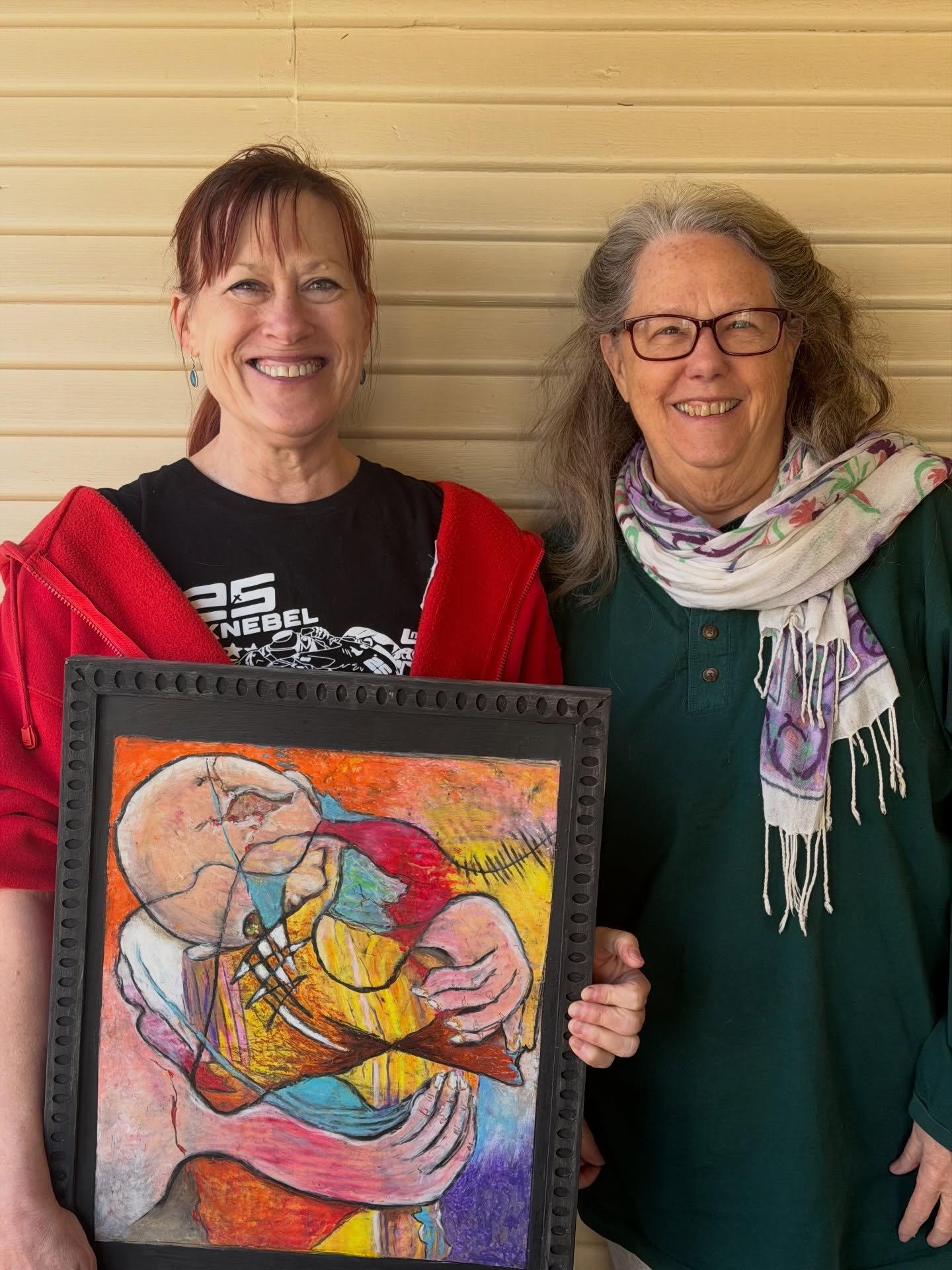 Denise Knebel holds up a recent painting at Art Spark Texas with Celia Hughes
