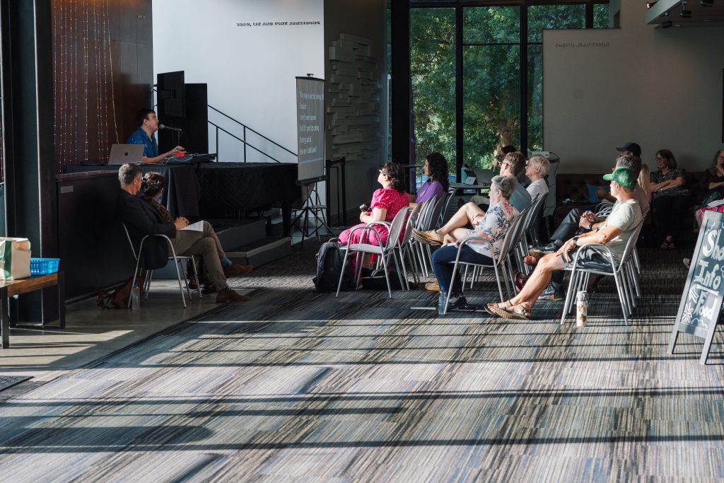 Panned out images of Devin playing the showcase to audience members at Zach Theater's Topfer Lounge