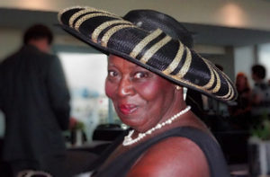 A smiling woman wearing a brimmed black and white hat.