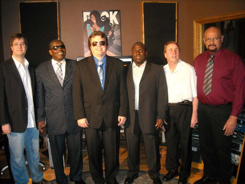 six musicians in a studio pose for a photo