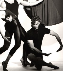 Dancer poses with arms forming a large circle in front of him. 