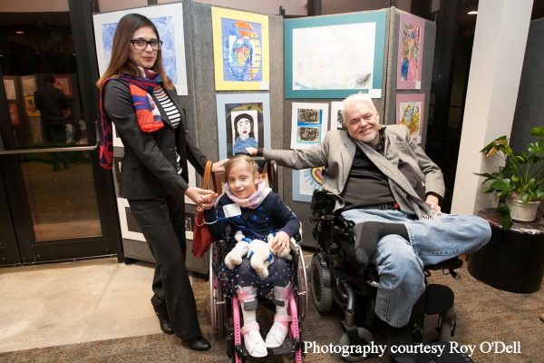 Randy with young artist in wheelchair and mother with visual art in background