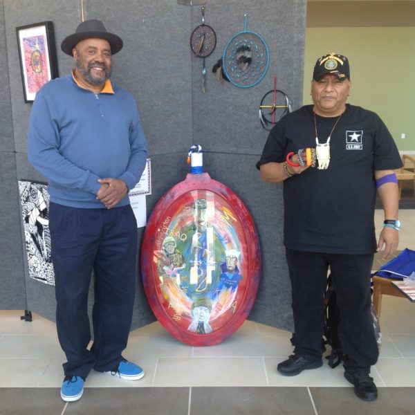 Photo of Glenn and fellow veteran Albert displaying their art at the Austin VA Outpatient Clinic.