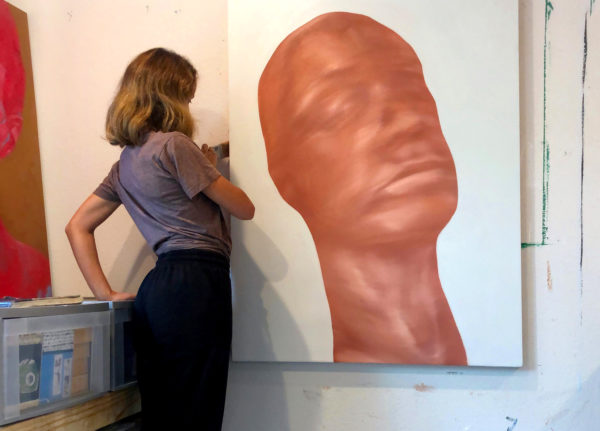 Hannah Lee painting a large portrait in her studio