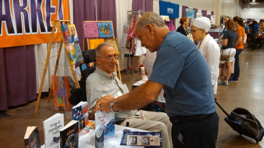 A customer browses an offering of books at Ron Hull’s artist market booth at the abilities Expo
