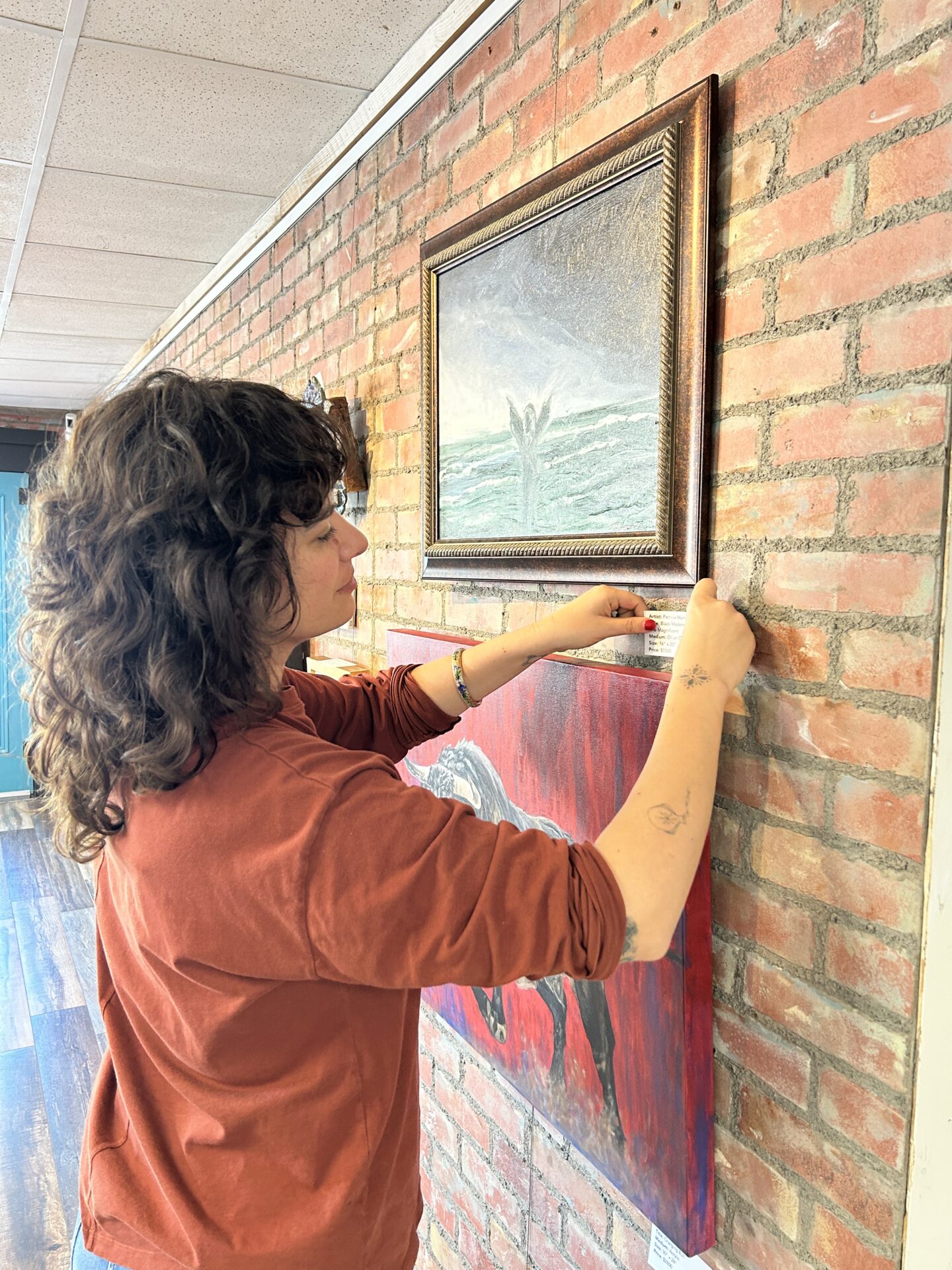 Kim Flor hangs the 16th Annual Distinguished Artist Veterans Exhibit at the Williamson County Art Guild Gallery with Art Spark Texas
