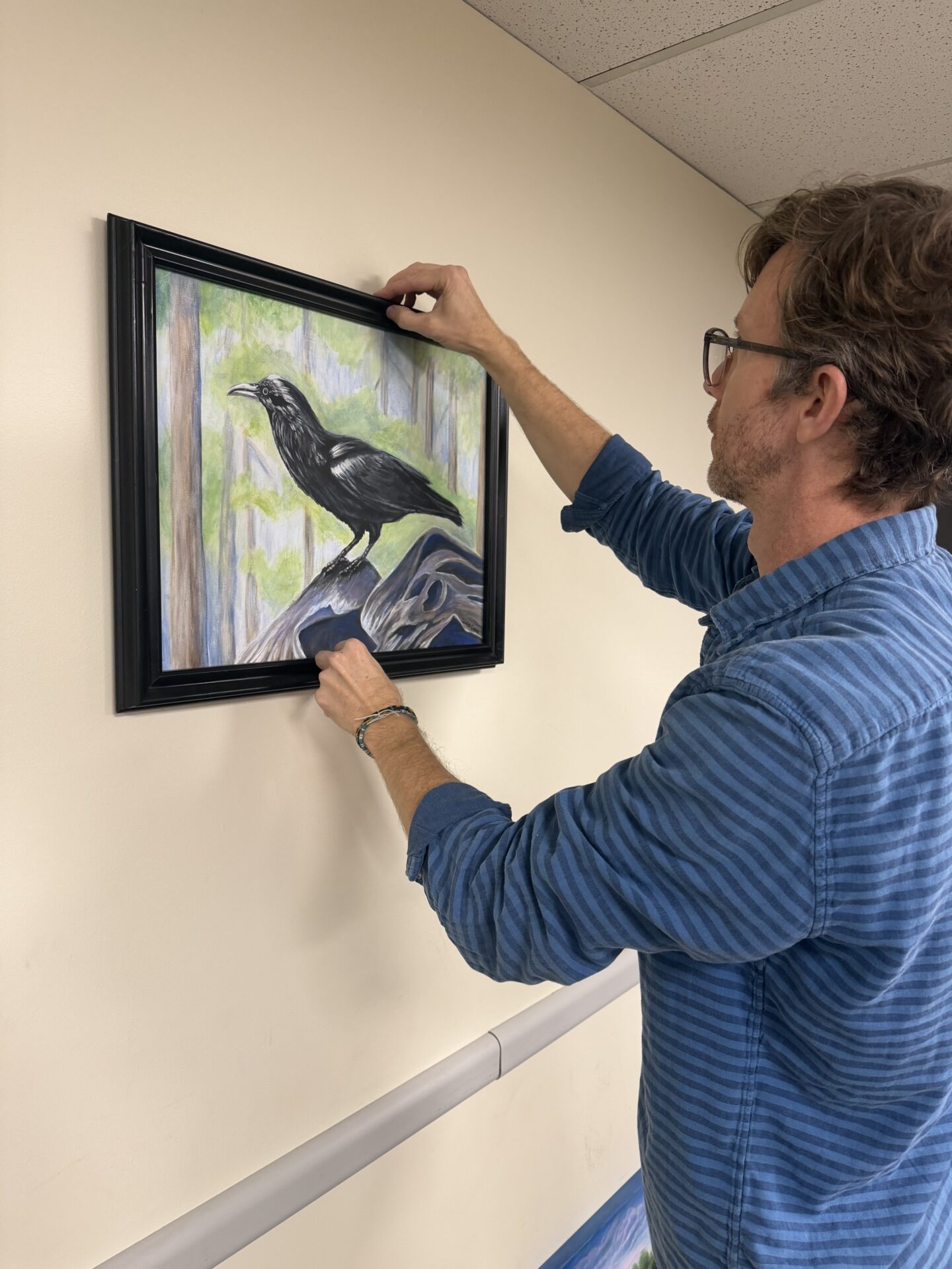 Jerry Slayton hangs Vision and Valor, a Texas Women's Veteran Art Exhibit at the Austin-Bergstrom International Airport with Art Spark Texas