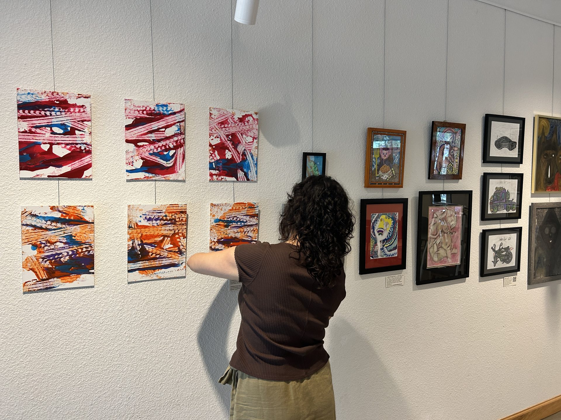 Kim Flor installs Jonah Dillon's wheelchair paintings at the All for Art exhibit at Imagine Art