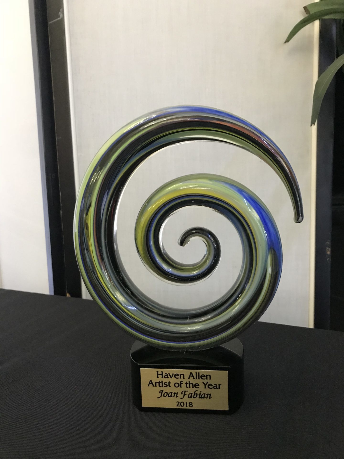 colorful glass spiral with plaque underneath reading Haven Allen Artist of the Year Joan Fabian 2018