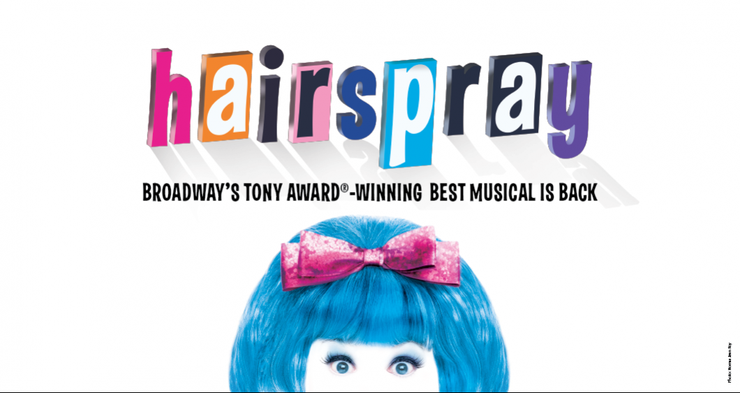 Promotinal graphic shows a wide-eyed woman with blue hair and a pink bow on top staring at the camera. Colorful text above her reads, "Hairspray, Broadway's Tony Award-Winning Best Musical is Back."