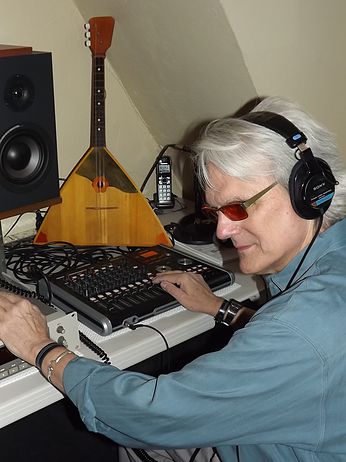A color photo shows Jeff wearing headphones and adjusting knobs on a mixing board in his studio. A speaker and antique folk instrument are visible in the background.