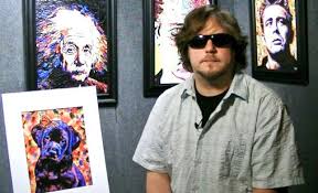 John posing with his vibrant paintings of Einstein, Johnny Cash, and others