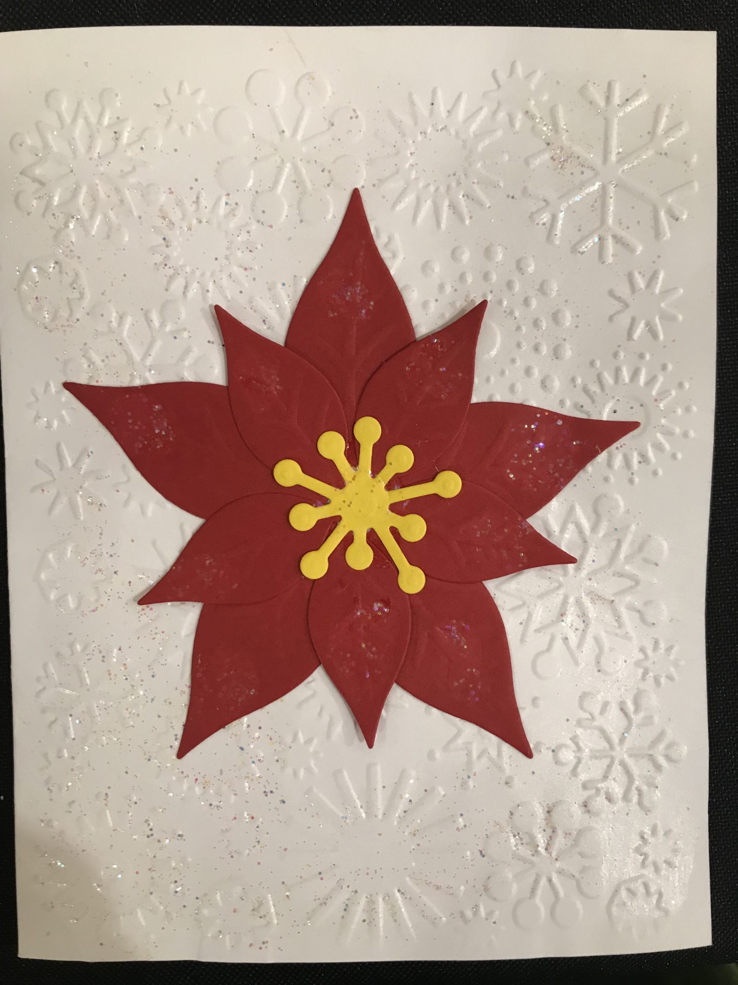 Tactile red poinsettia collage on white paper embossed snowflakes