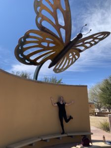 Woman posing under giant metal butterfly
