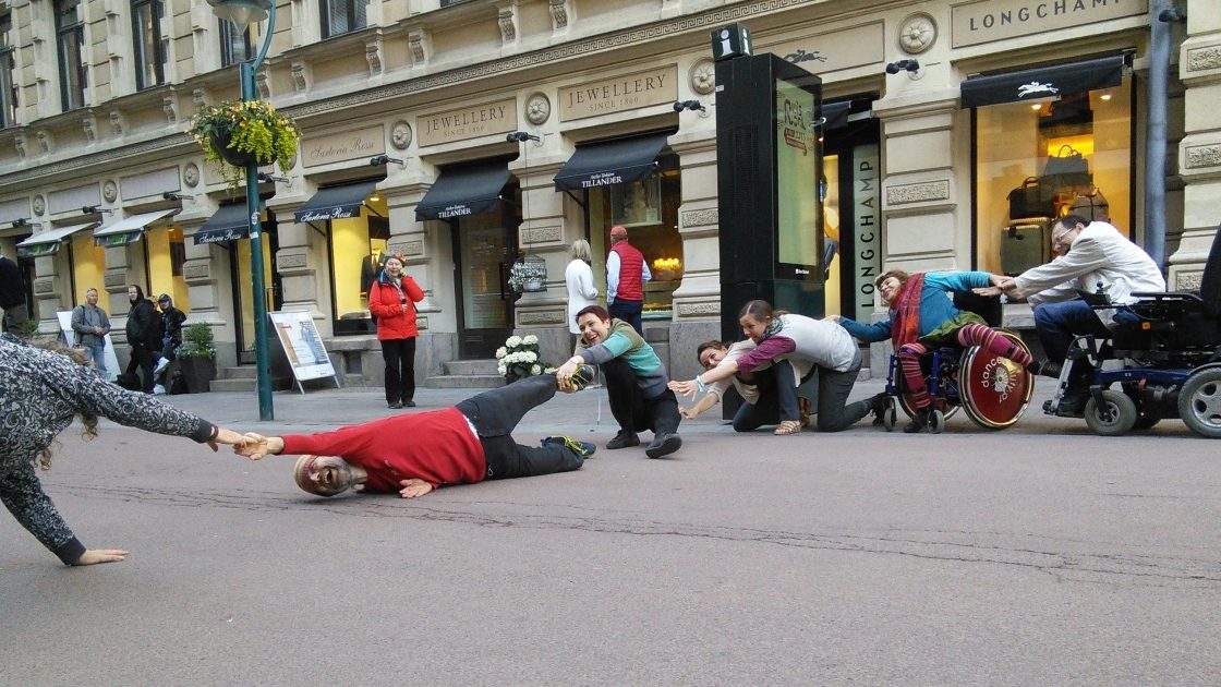 dancers with and without disabilities perform outside on a city street. 