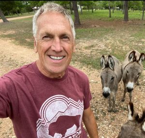 A man standing outside with donkeys