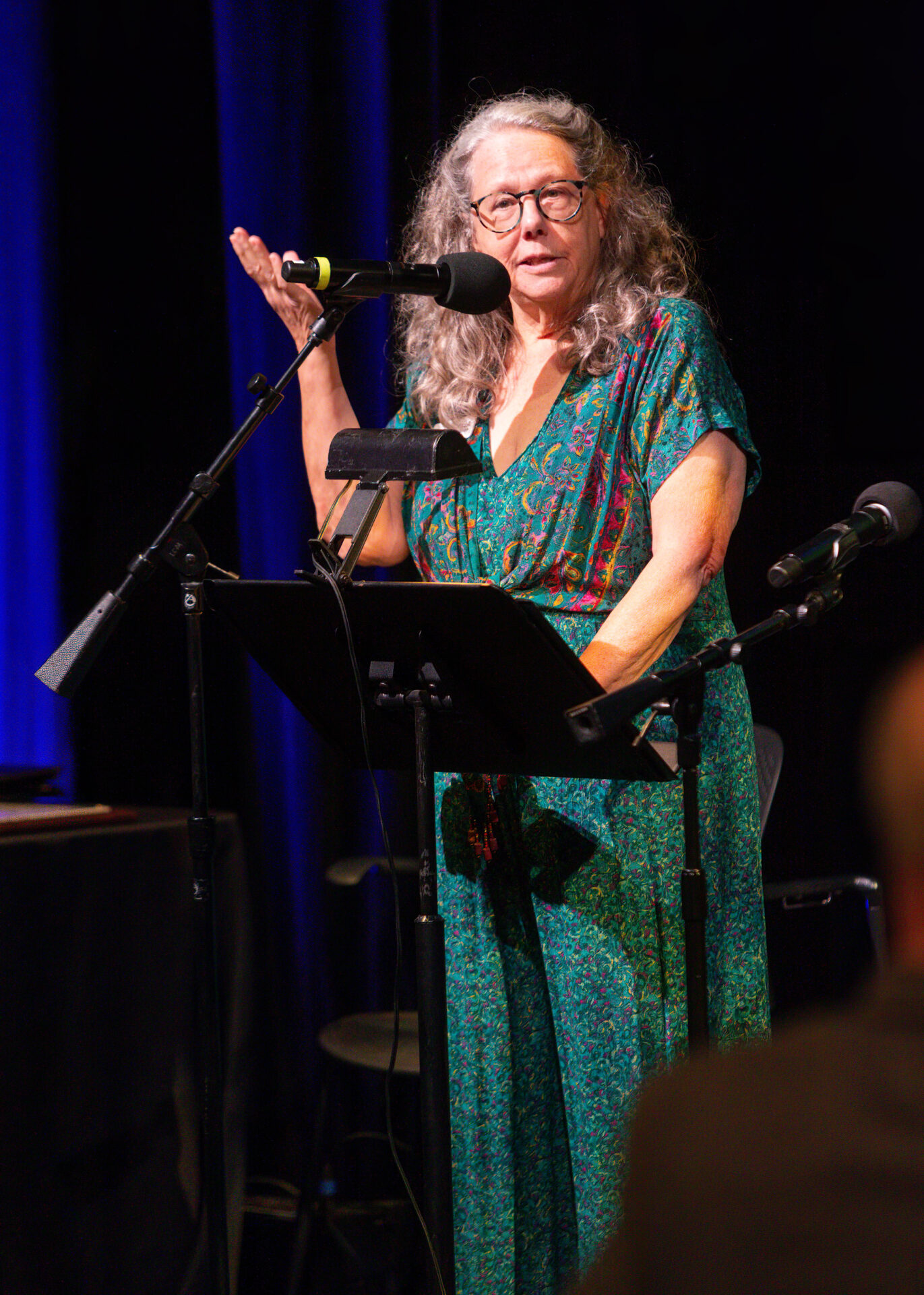 Celia Hughes, the Executive Director of Art Spark Texas, greets the guests of the Artist of the Year awards ceremony in a long emerald and red dress.