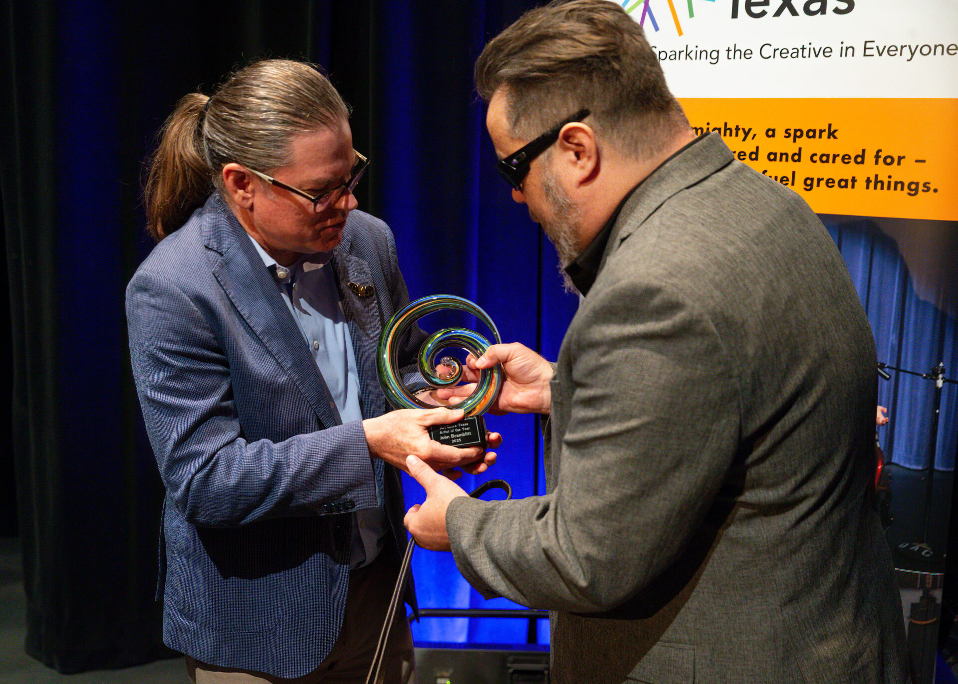 John Bramblitt, a blind painter and artist of the year award winner 2025, accepts his award from art spark texas board member.