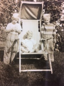 toddler sitting in a chair in between two young boys
