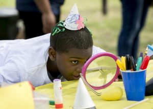 boy doing art at a table and looking in mirror