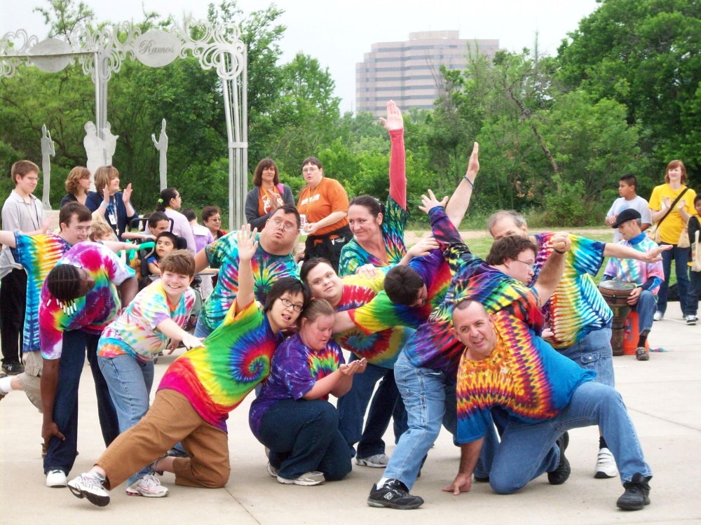 Group in tie dyed shirts posing with hands in air