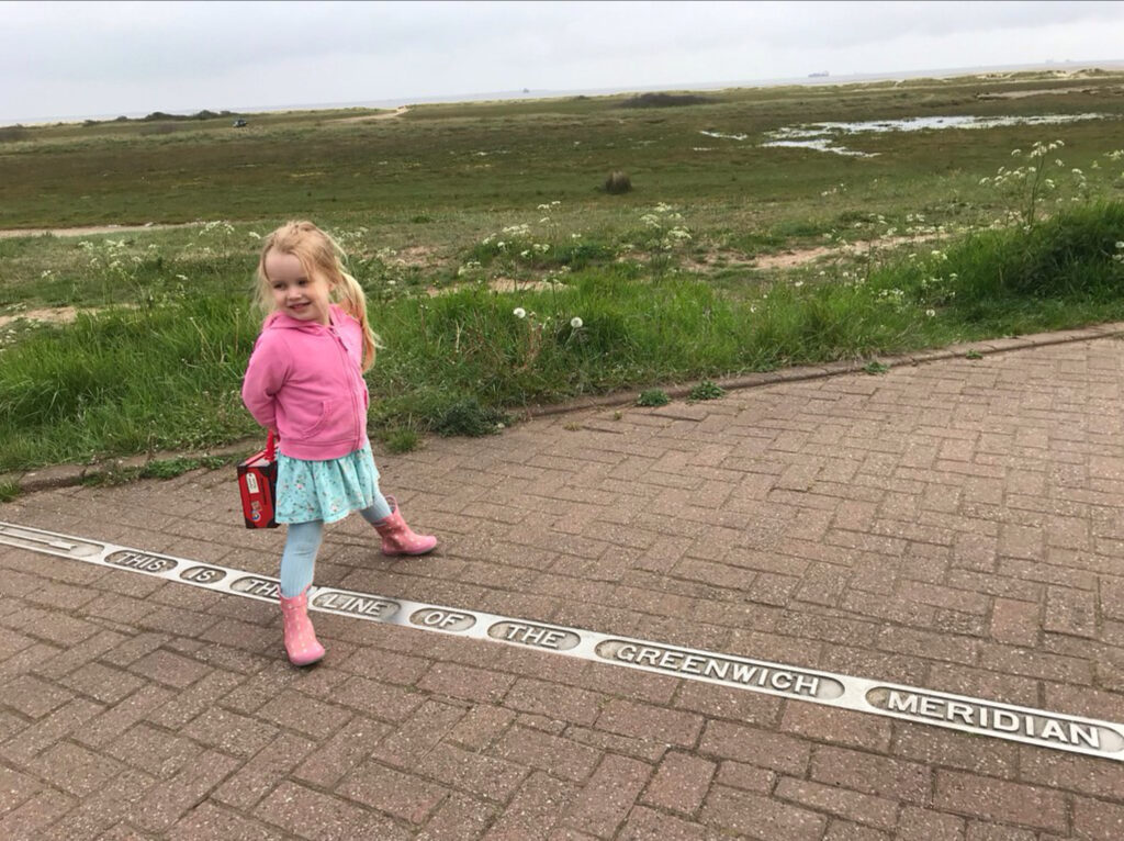 A young girl straddling the Greenwich Meridian.