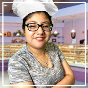 student wearing chef's hat with dessert counter in background