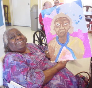 women proudly holding up her painting