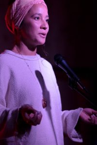 A woman singing at a Song Rise Arts event