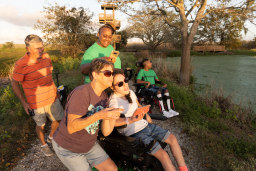 Group of adult and kids in wheelchairs at a park