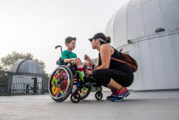 woman kneeling in front of a child in a wheelchair