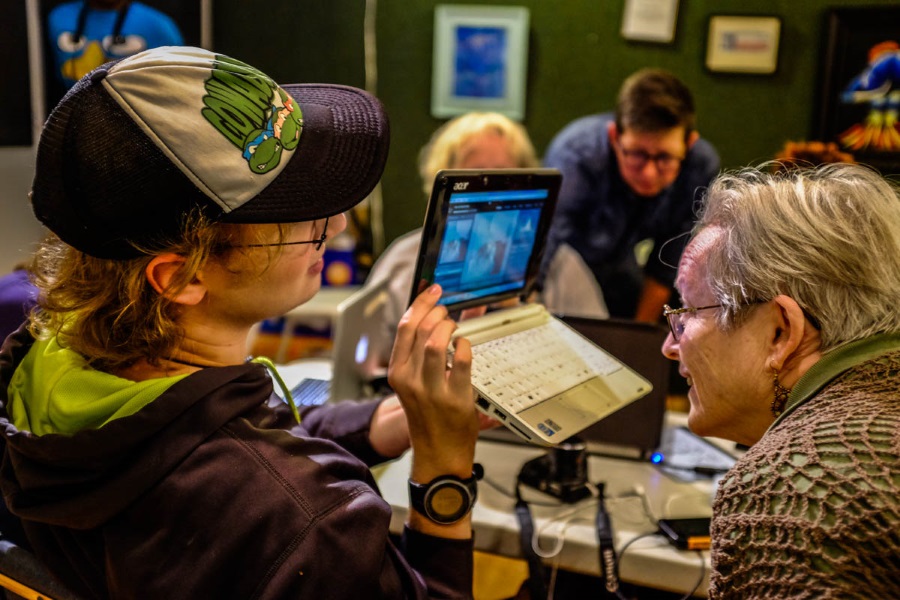 younger person teaching an older woman on a computer