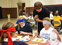 John supervising blindfolded children as they finger paint